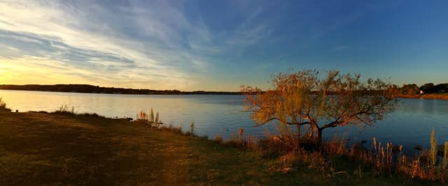 Warm sunset over Inks Lake in the Texas Hill Country, golden light on autumn foliage beside calm water